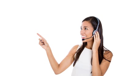Close-up portrait of a smiling adorable female customer representative talking on a hands free phone pointing at a copy space, isolated on a white background